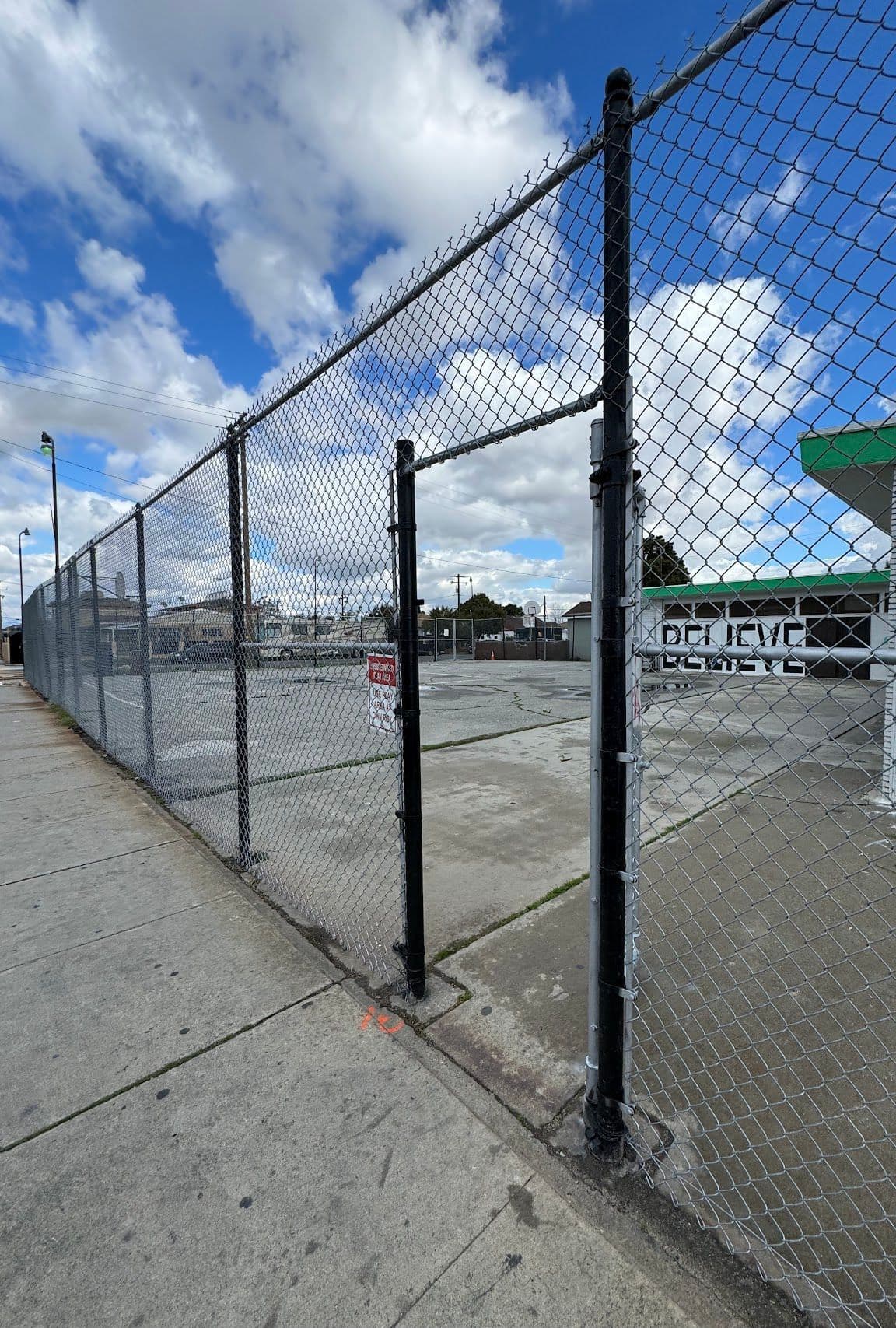 Chain-link fence line with a gate opening and top rail