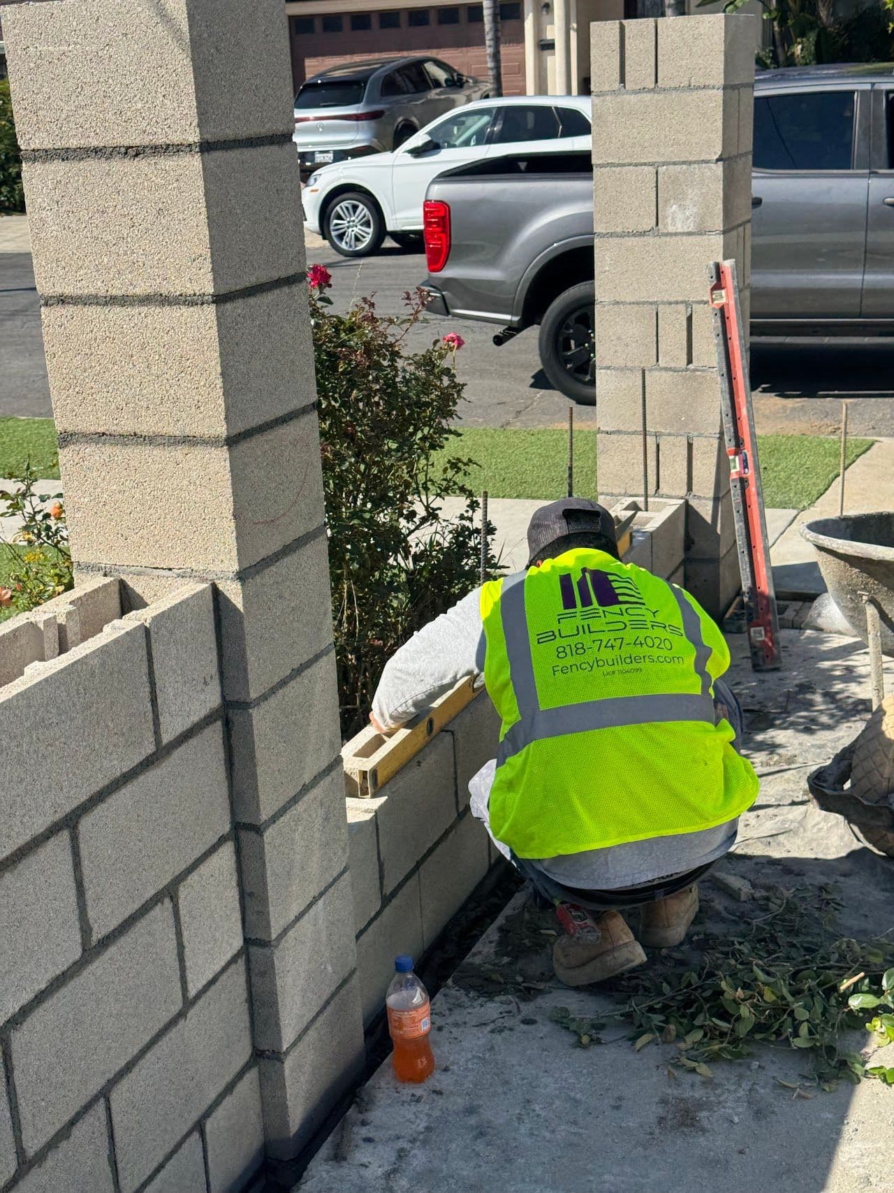 Fency Builders crew member laying block between new pillars