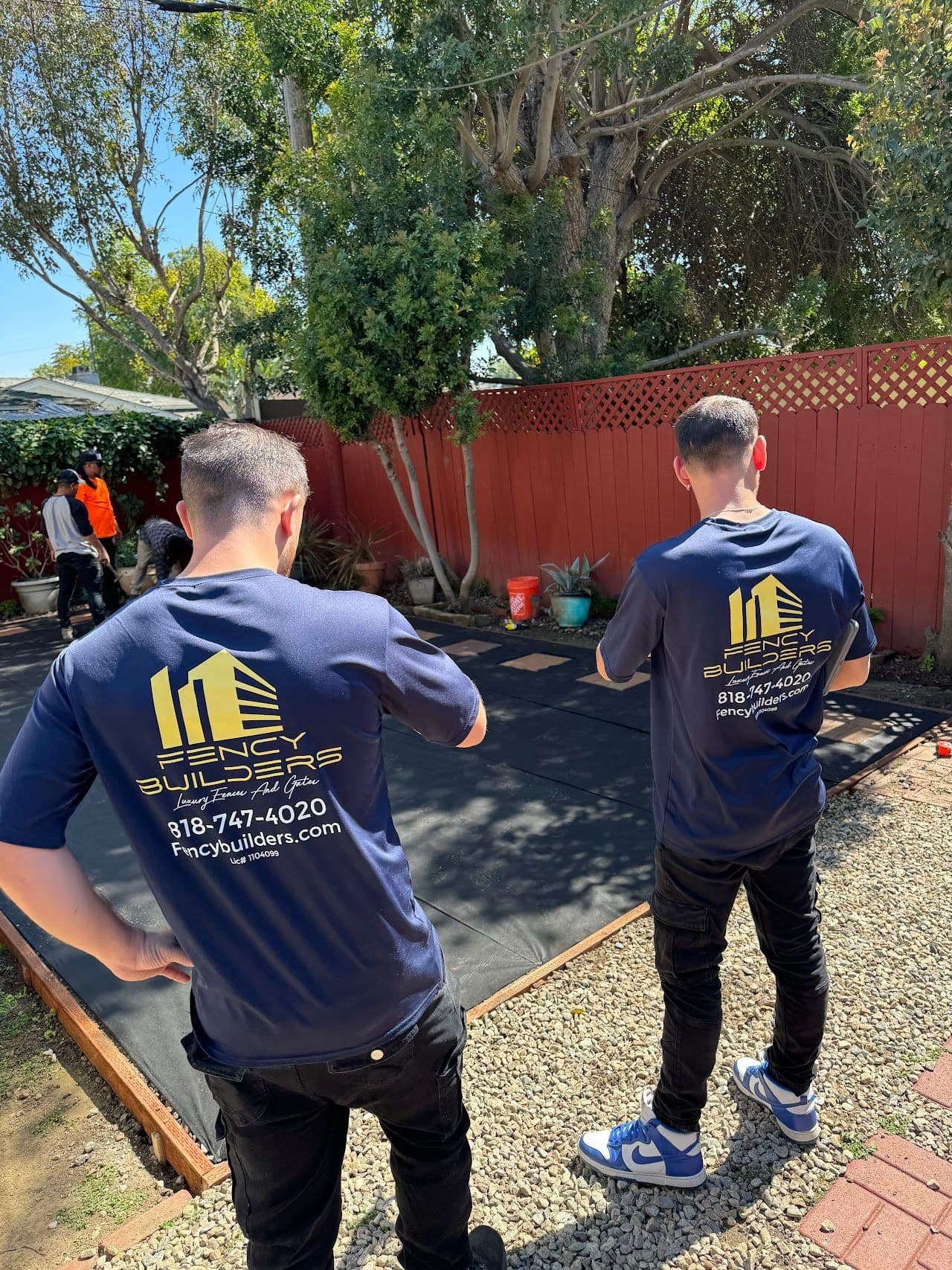 Two Fency Builders team members walking a backyard job in progress