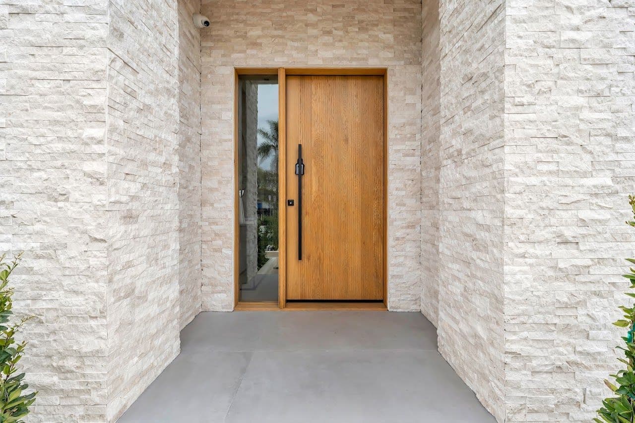 Oak front door framed by stacked white stone at the entry of a new home