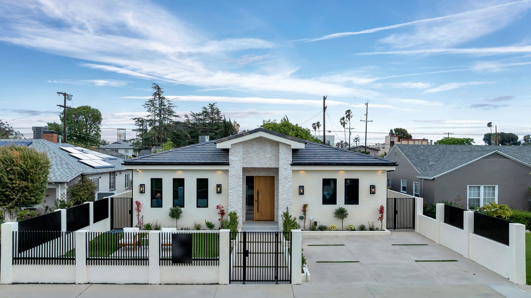 Elevated view of a new home behind a black metal fence with matching driveway and walk gates