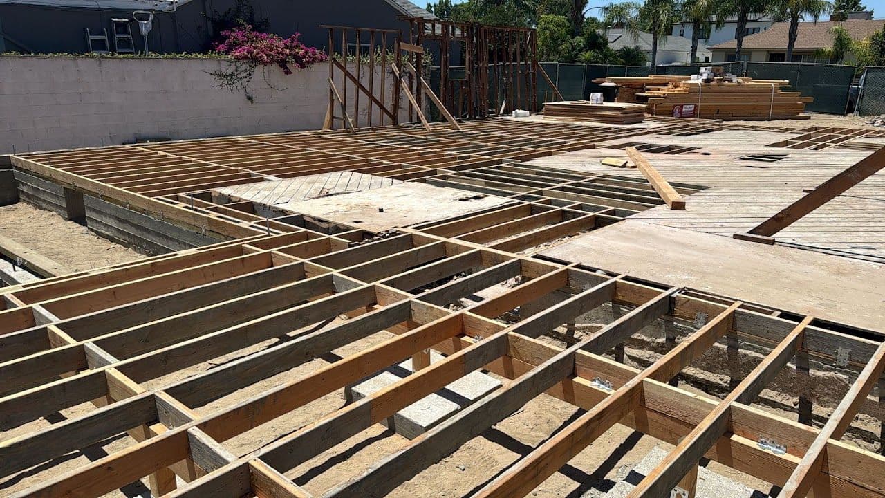 Floor framing on a new-construction site, joists and sheathing laid over the foundation