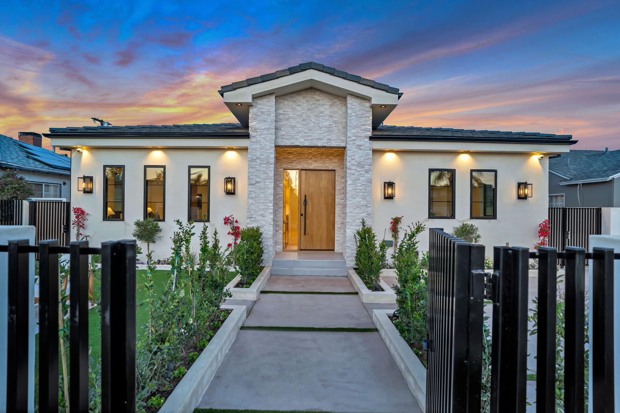 View through a black steel walk gate up the front path to a new home at dusk