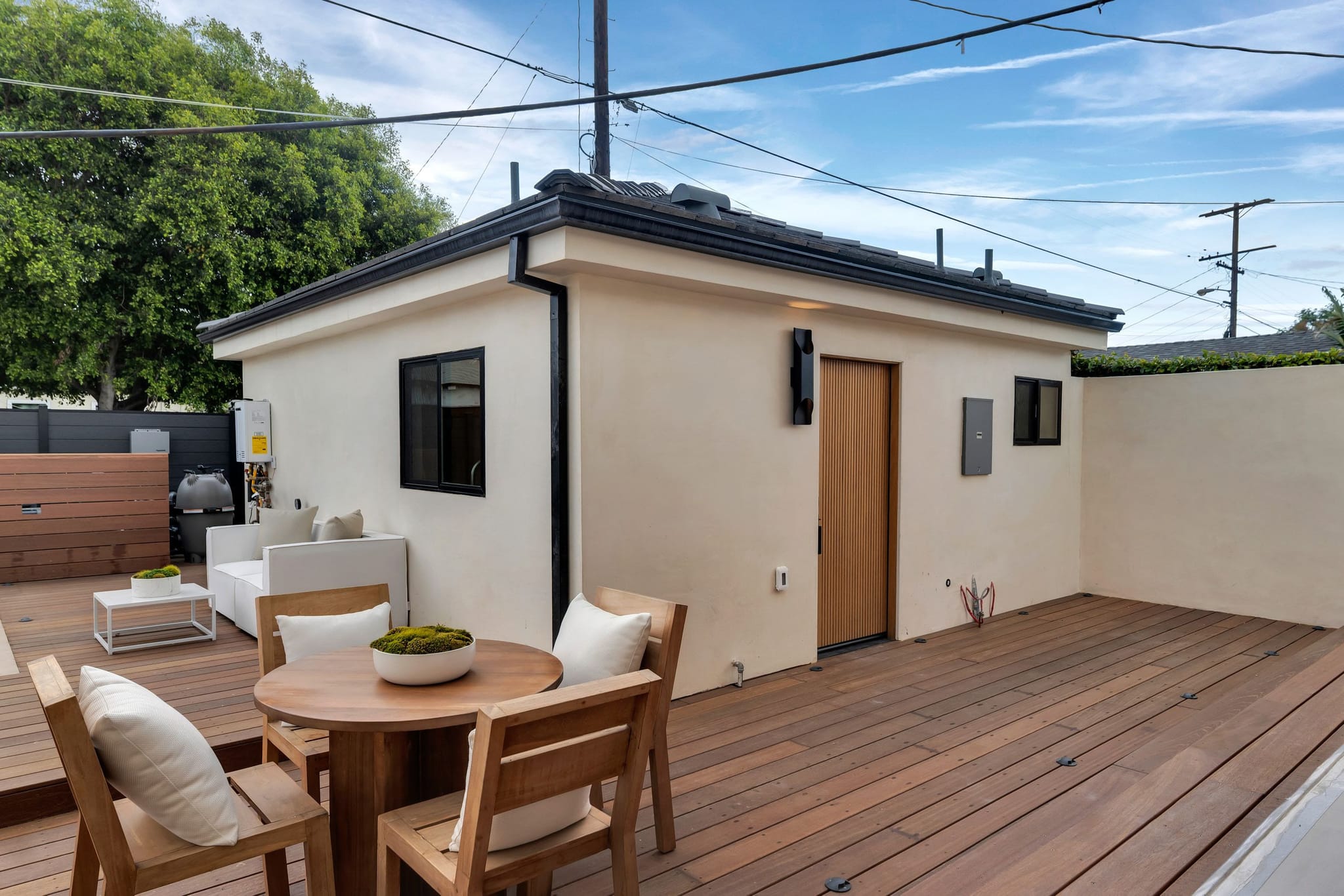 Hardwood deck leading to a detached stucco building at the back of the yard
