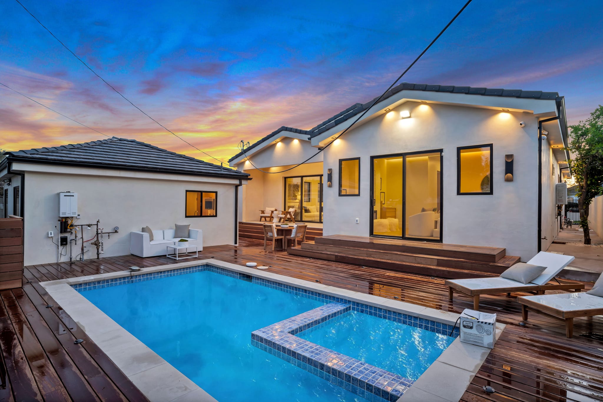 Pool and hardwood deck behind a new home at twilight