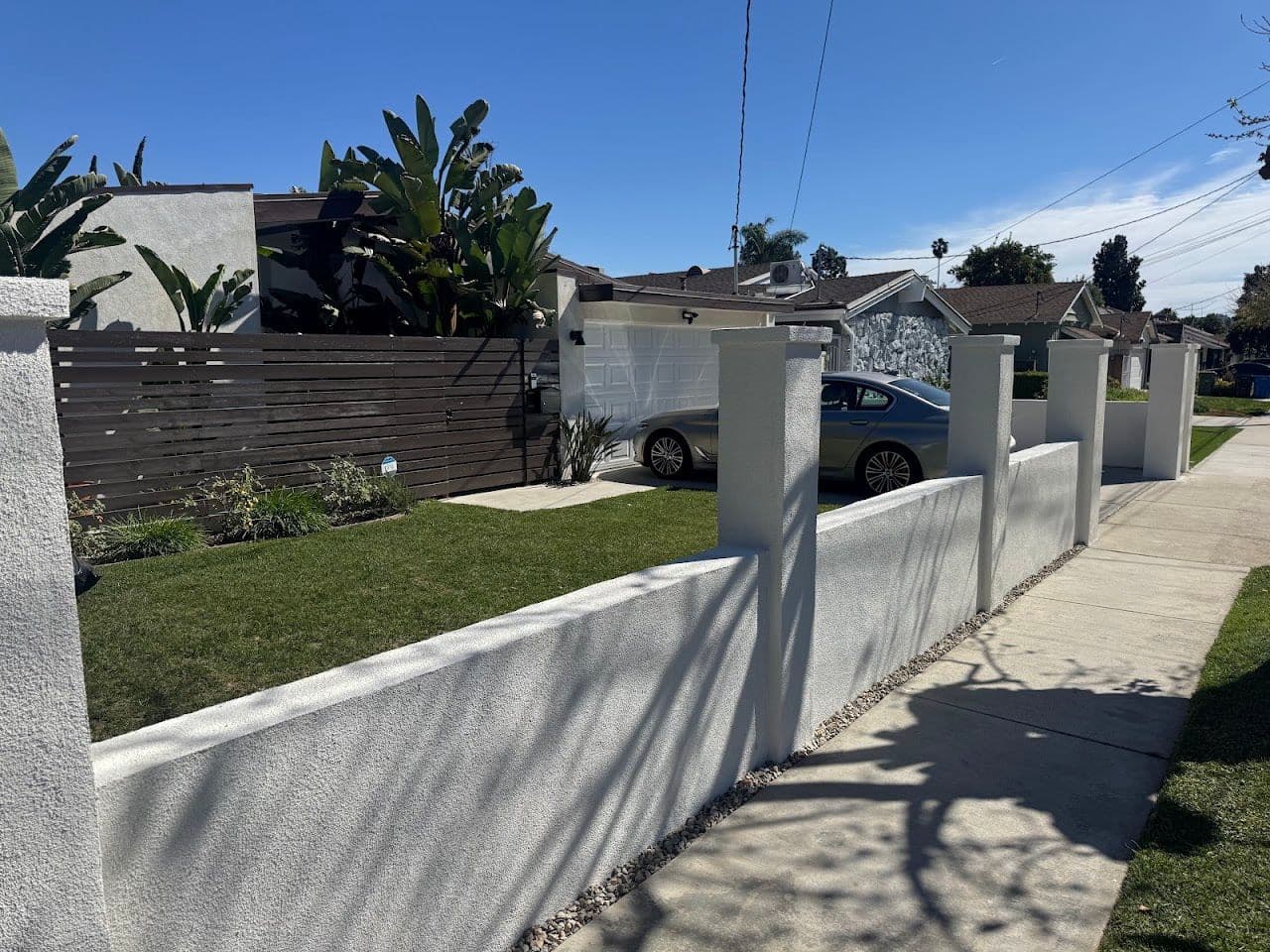 White stucco garden wall along a front lawn and sidewalk