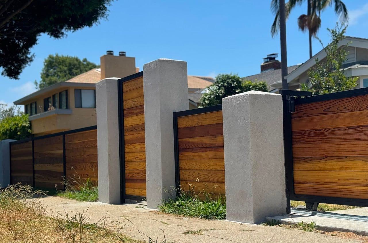 Horizontal wood fence panels between smooth stucco pillars along a front yard