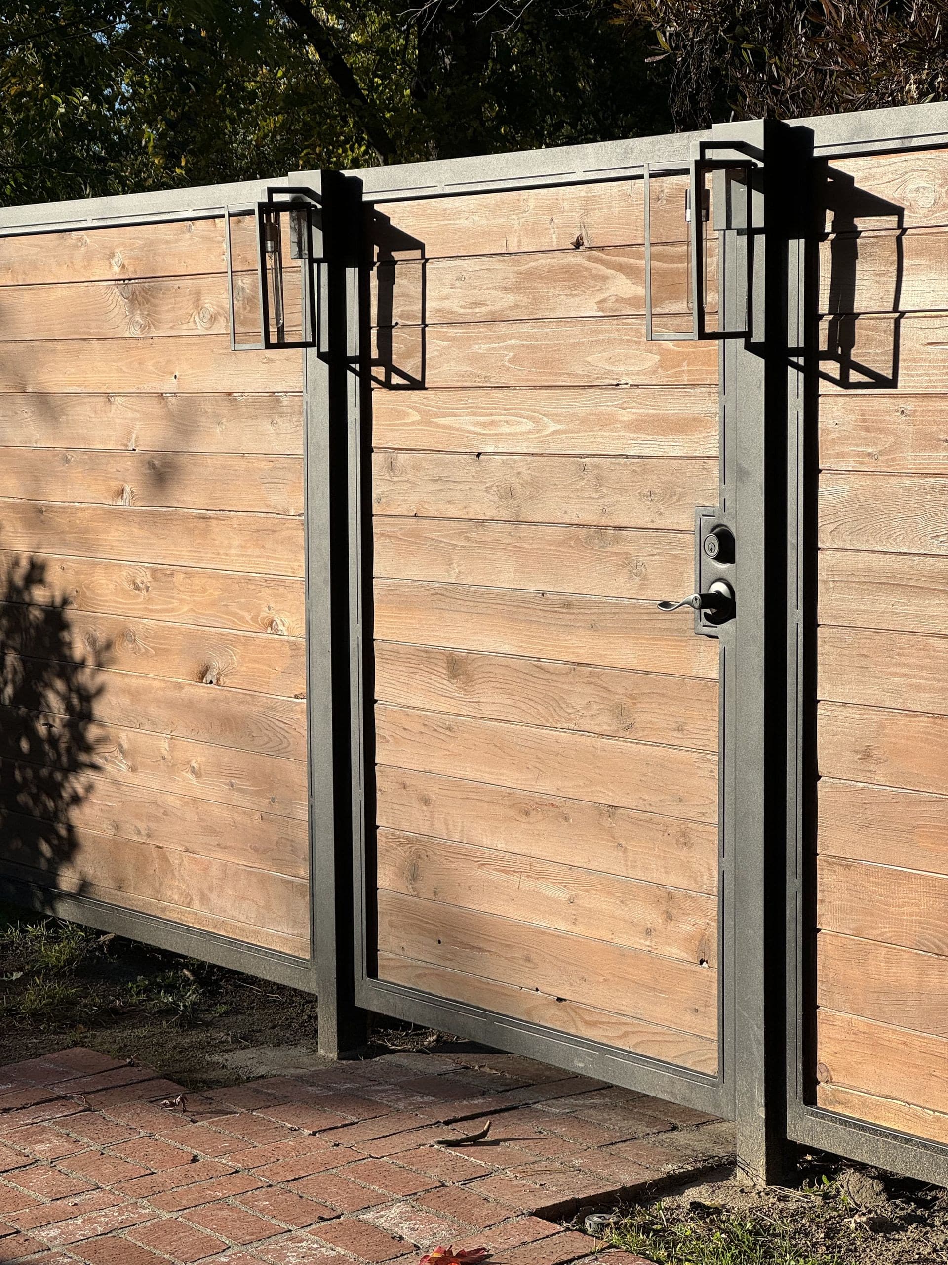 Wood and steel walk gate with black lanterns in late-afternoon light