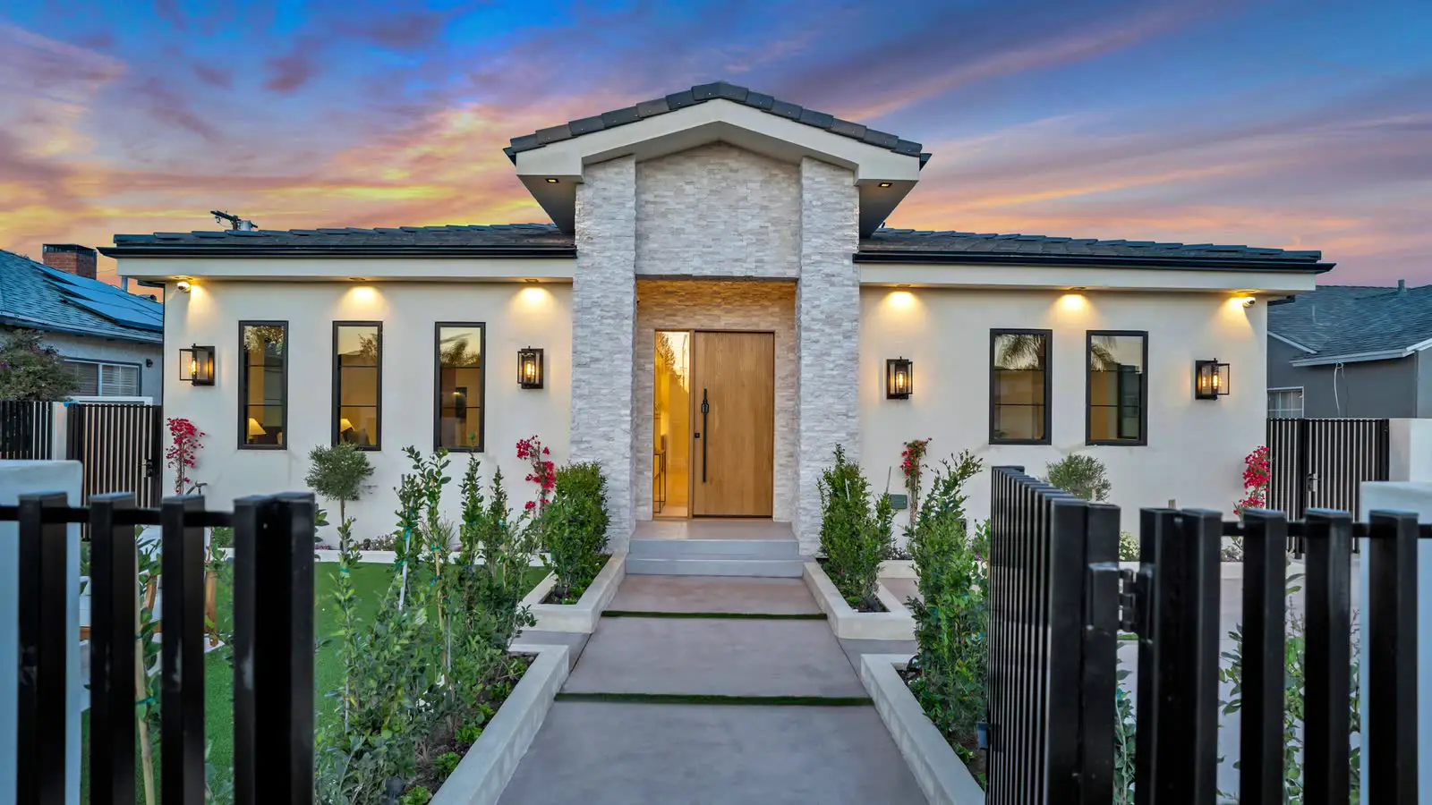 A new single-story home at dusk, seen through the open front gate